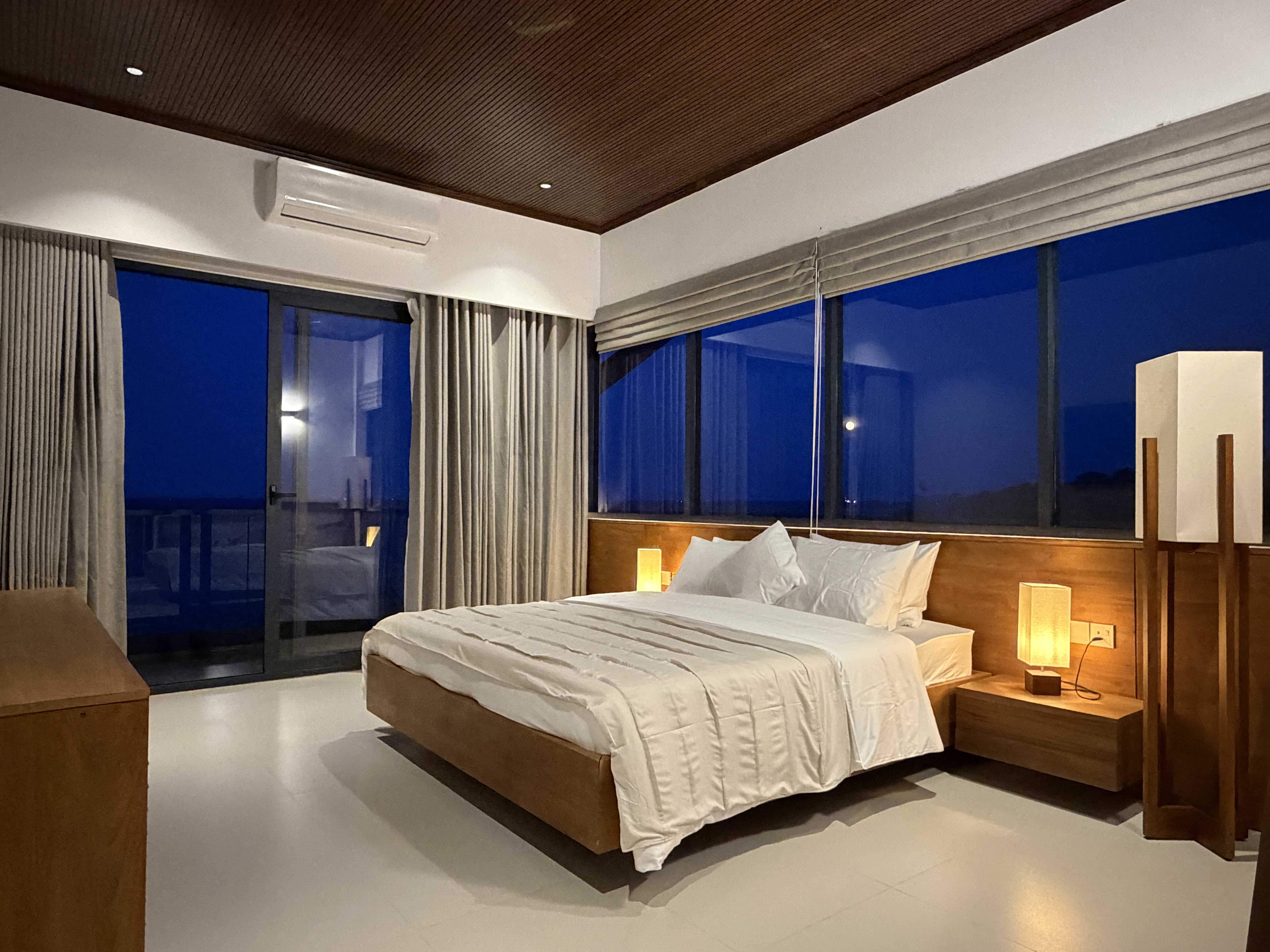 A sea-facing room with the balcony doors open.
